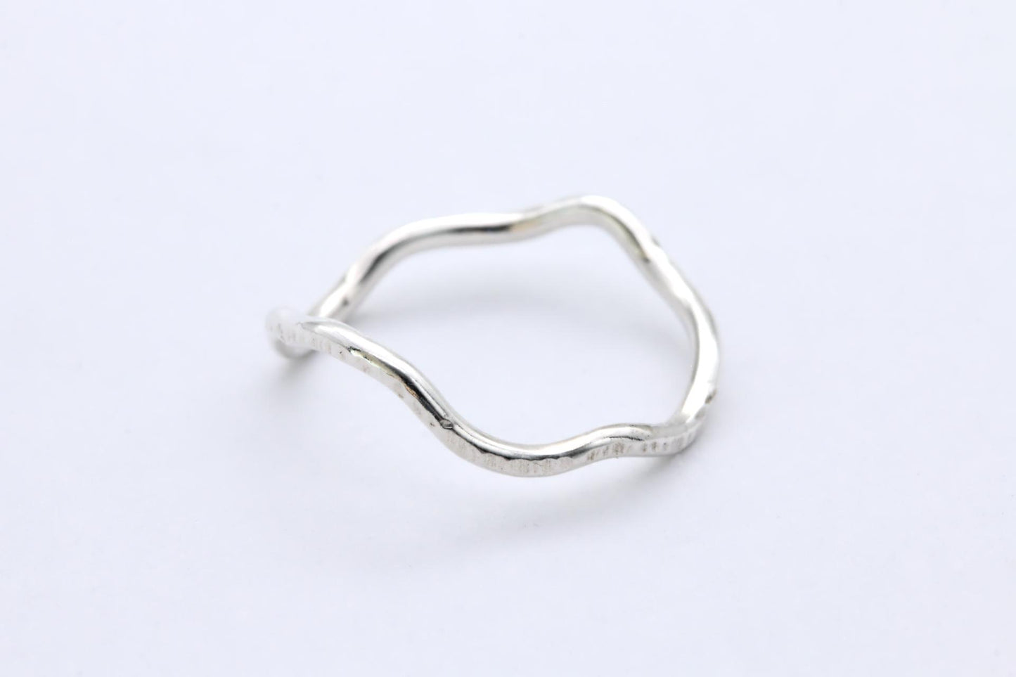 A silver wavy abstract ring on a white background